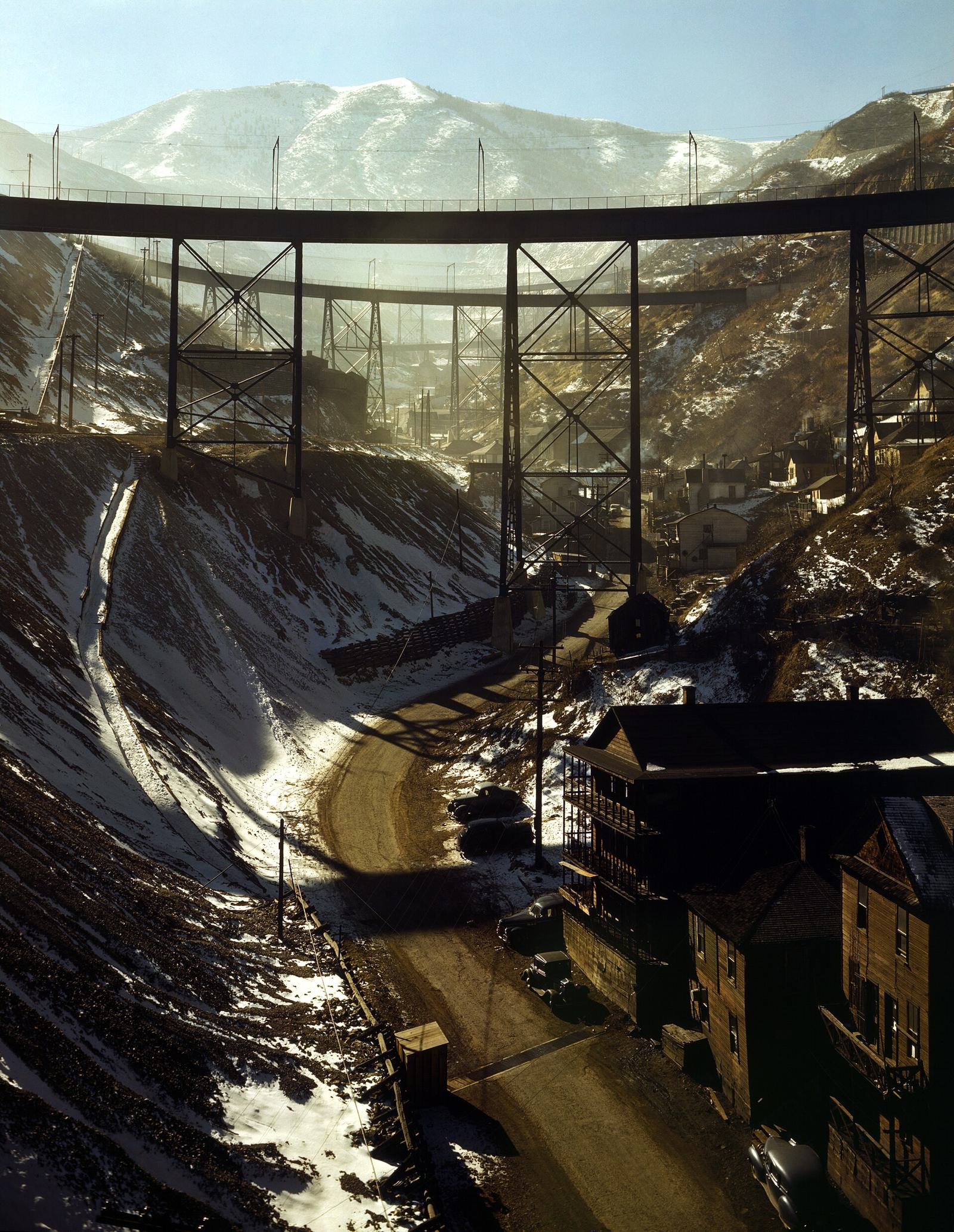 A steel railway trestle crossing a snowy canyon above mining houses