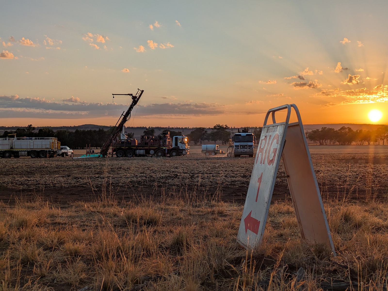 Une foreuse sur une plaine de broussailles au lever du soleil, avec un panneau qui indique le chantier