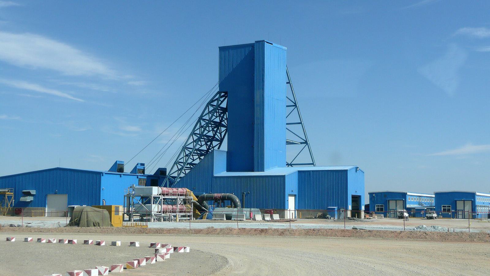 Un grand chevalement bleu et des bâtiments industriels dans le désert de Gobi